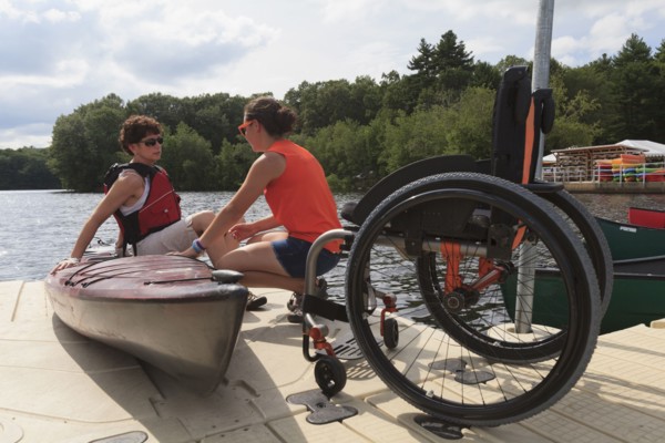 Caucasian instructor helping paraplegic woman with kayak