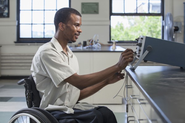 African American paraplegic student performing experiment in science classroom