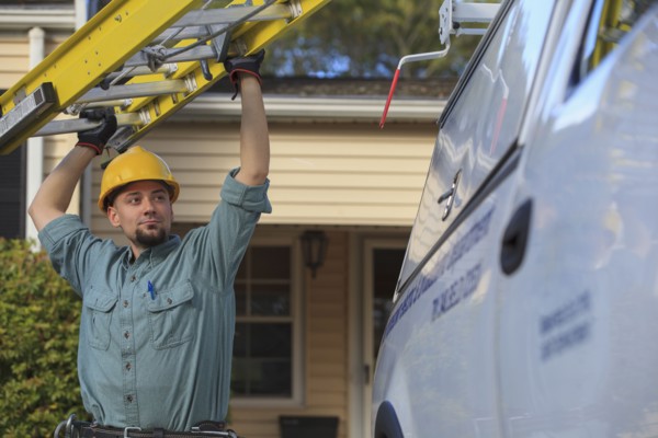Caucasian worker pulling ladder from truck roof