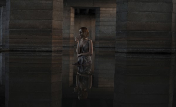 Caucasian woman standing in water smoking cigarette