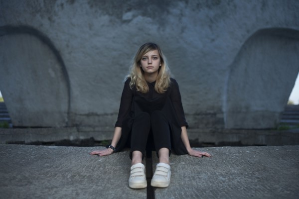 Portrait of serious Caucasian woman sitting on concrete