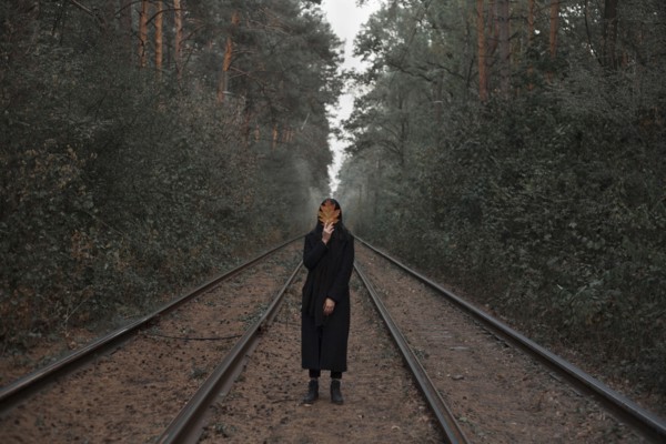 Caucasian woman holding autumn leaf on train tracks in forest