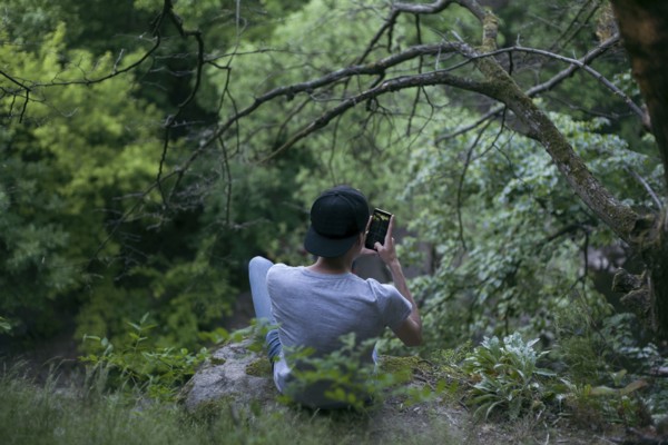 Caucasian man texting on cell phone in woods