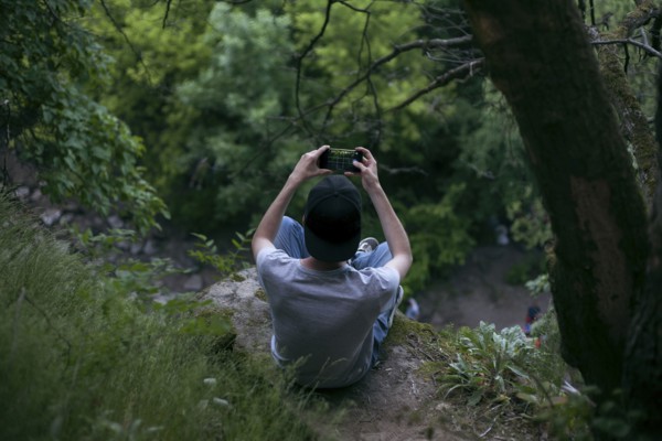 Caucasian man photographing with cell phone in woods