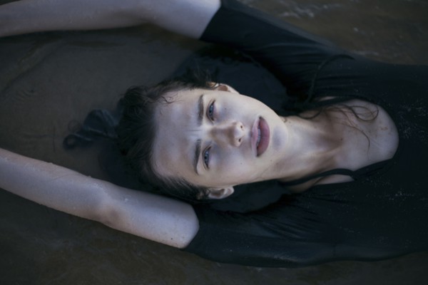 Caucasian woman laying on beach in waves