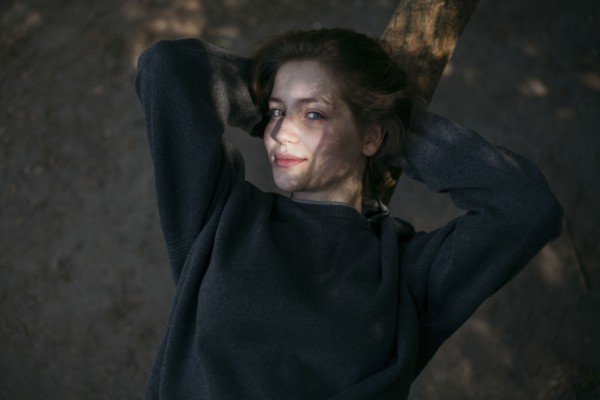 Portrait of smiling Caucasian teenage girl leaning on tree