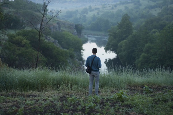 Caucasian man standing on hill above river