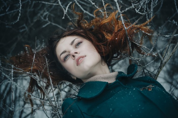 Serious Caucasian woman laying on icy branches