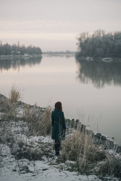Caucasian woman standing near river in winter