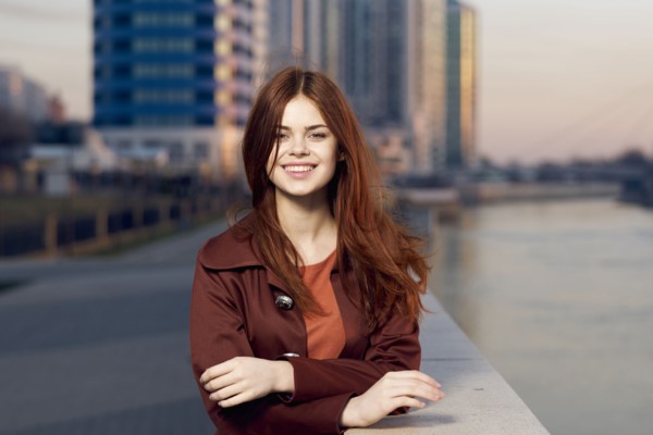Smiling Caucasian woman leaning on wall at waterfront
