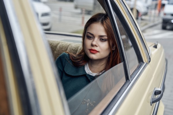 Pensive Caucasian woman in back seat of car