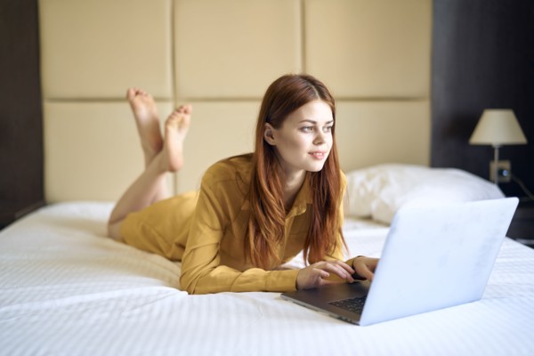Caucasian woman laying on bed using laptop