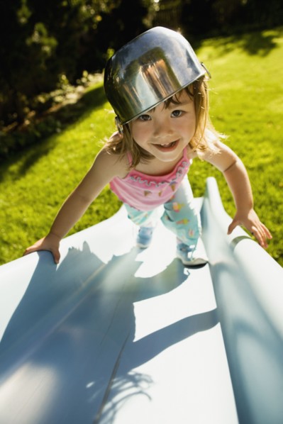 Portrait of girl climbing slide with bowl on head