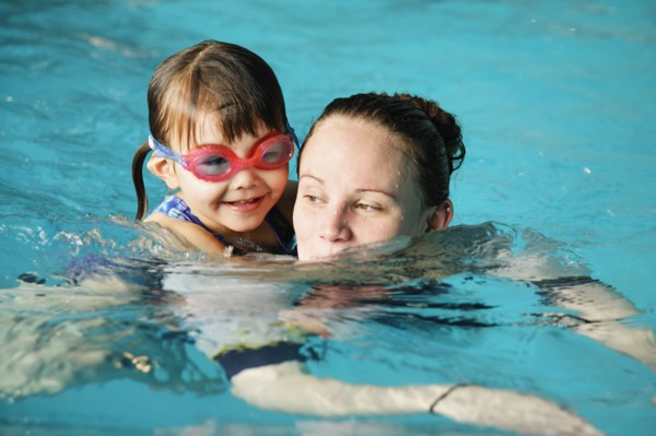 Mother and young daughter swimming