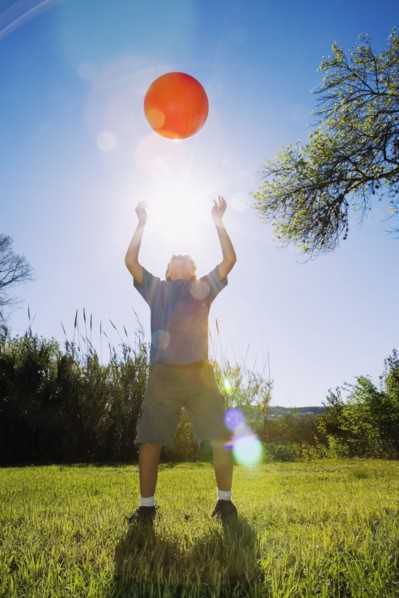 Boy throwing ball in bright sunlight