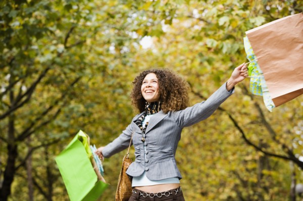 Hispanic woman swinging shopping bags in park