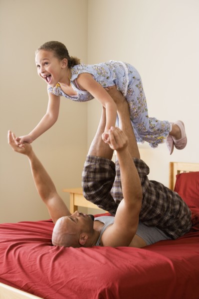 African girl balancing on father's feet