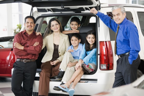 Hispanic family with salesman at car dealership