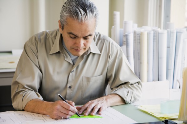 Hispanic male architect writing at desk