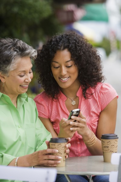 African American mother and adult daughter looking at cell phone