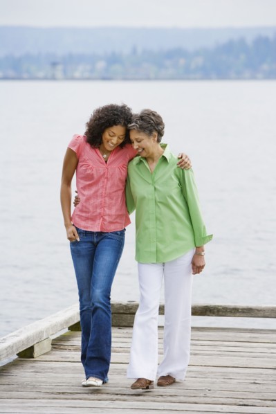 African American mother and adult daughter walking on pier