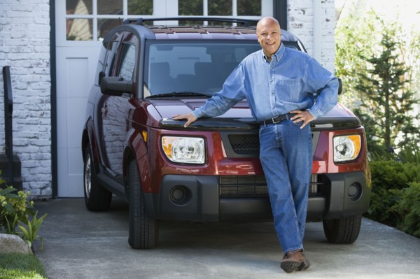 Senior African American man leaning on car