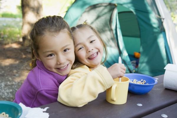 Asian sisters eating at campsite