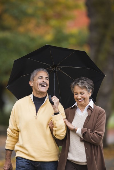 African couple walking with umbrella in autumn