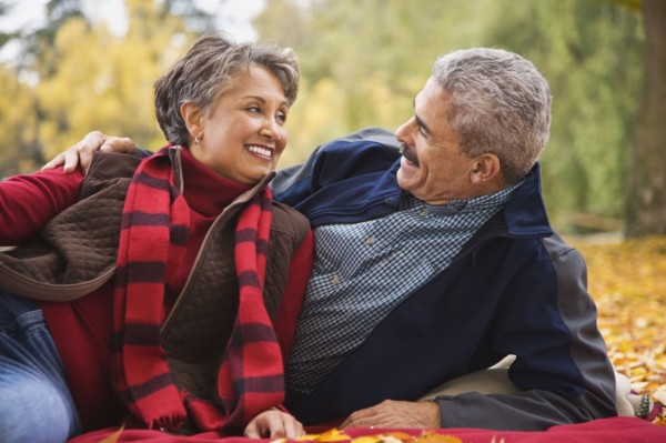 African couple laying on blanket among autumn leaves