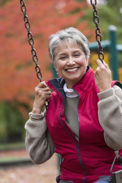 Mixed race woman on swing in park