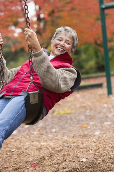 Mixed race woman on swing in park