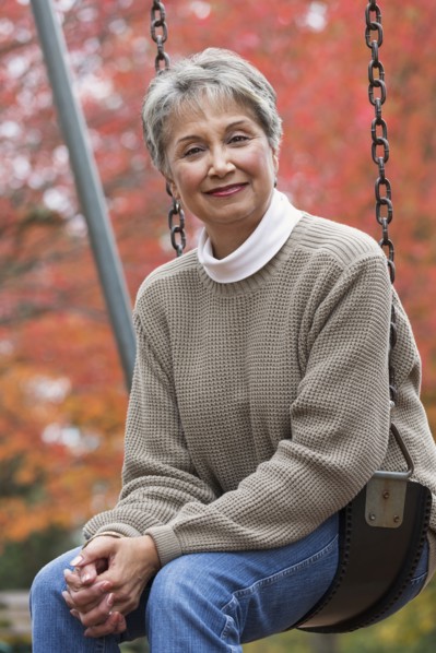 Mixed race woman on swing in park