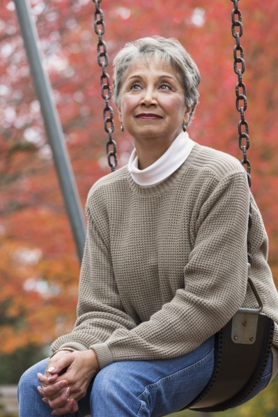 Mixed race woman on swing in park