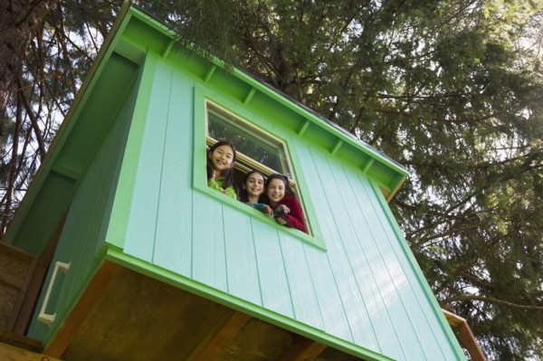 Girls leaning out tree house window
