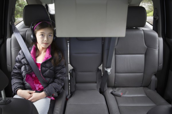 Mixed race girl watching television in backseat