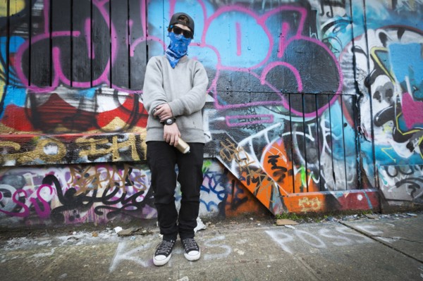 Caucasian teenage boy standing by graffiti wall