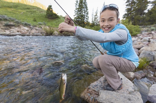 Mixed race girl fishing in river
