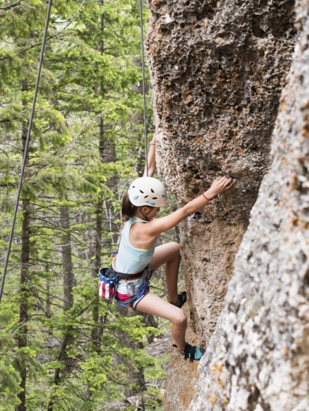 Mixed race girl climbing steep cliff