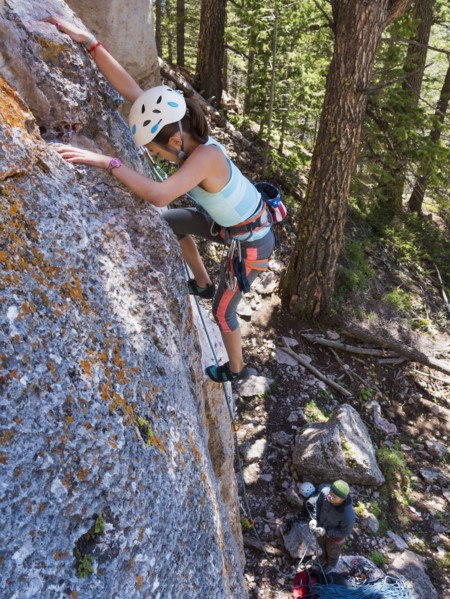 Mixed race girl climbing steep cliff