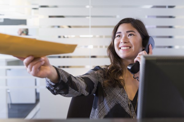 Mixed race businesswoman handing folder in office