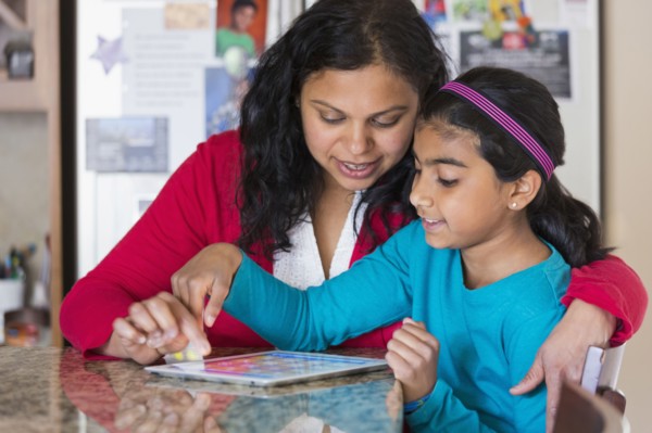 Indian mother and daughter using digital tablet at counter