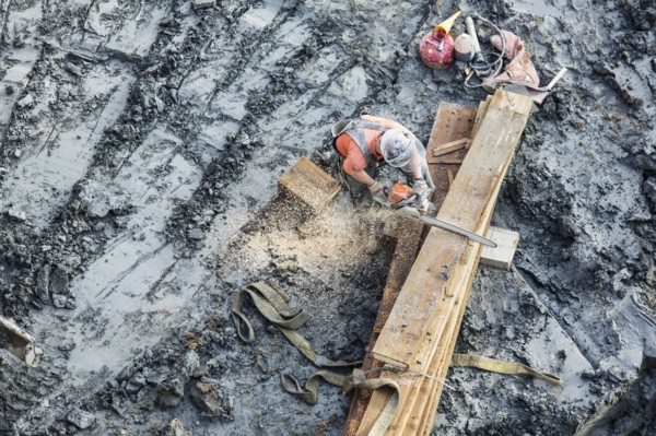Caucasian worker sawing wood at construction site