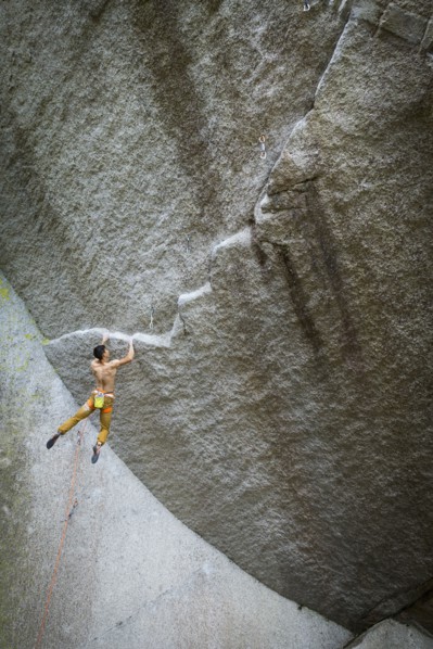 Mixed race boy hanging from rock