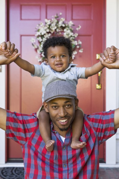 Smiling mixed race father carrying baby son on shoulders