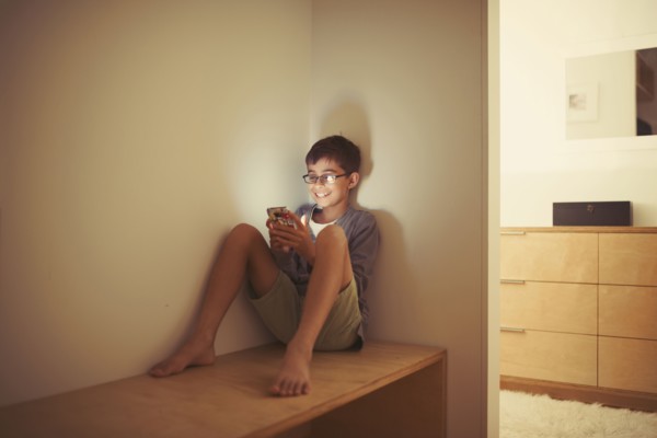 Mixed race boy using cell phone on bench