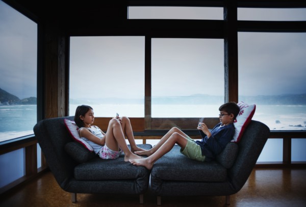 Mixed race children using cell phones in living room