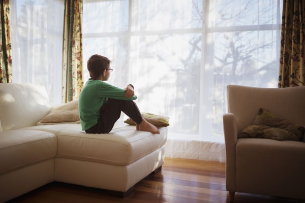 Mixed race girl looking out living room window