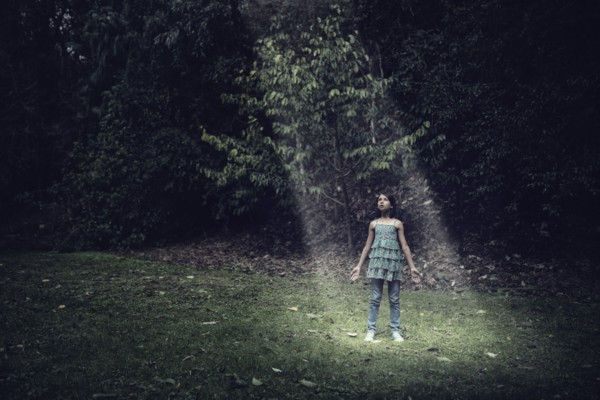 Mixed race girl standing in beam of light outdoors