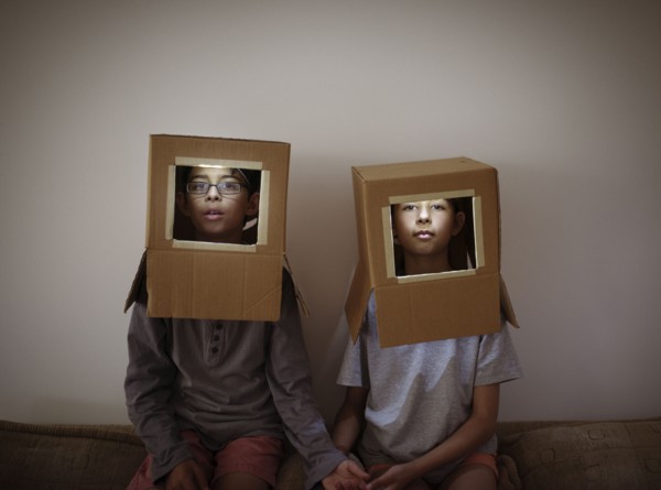 Mixed race brother and sister wearing cardboard box astronaut helmets