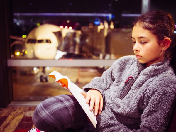 Mixed race girl reading book in airport
